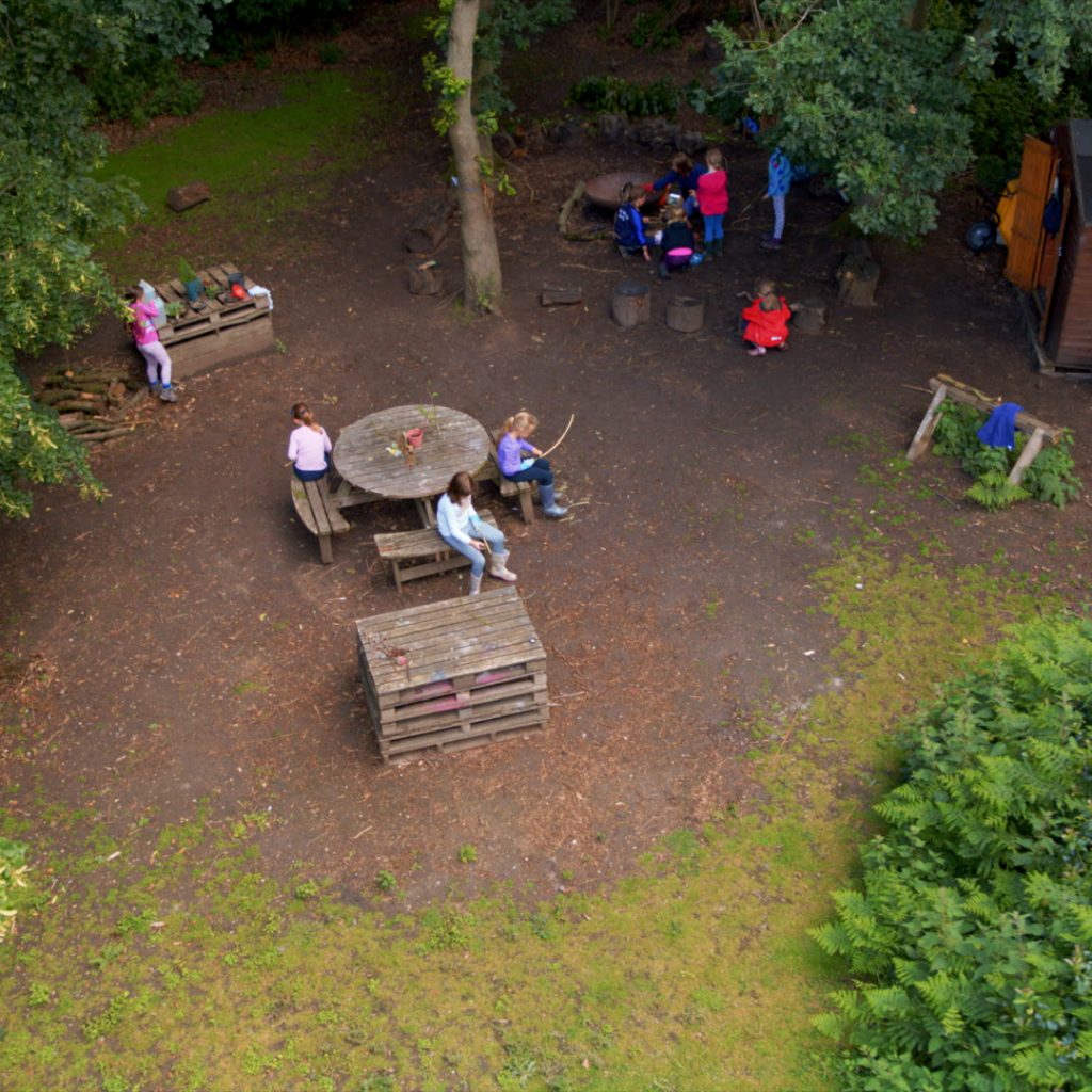 Aerial photo of St Mary's Colchester's Forest School, showing several pupils busy with different activities.