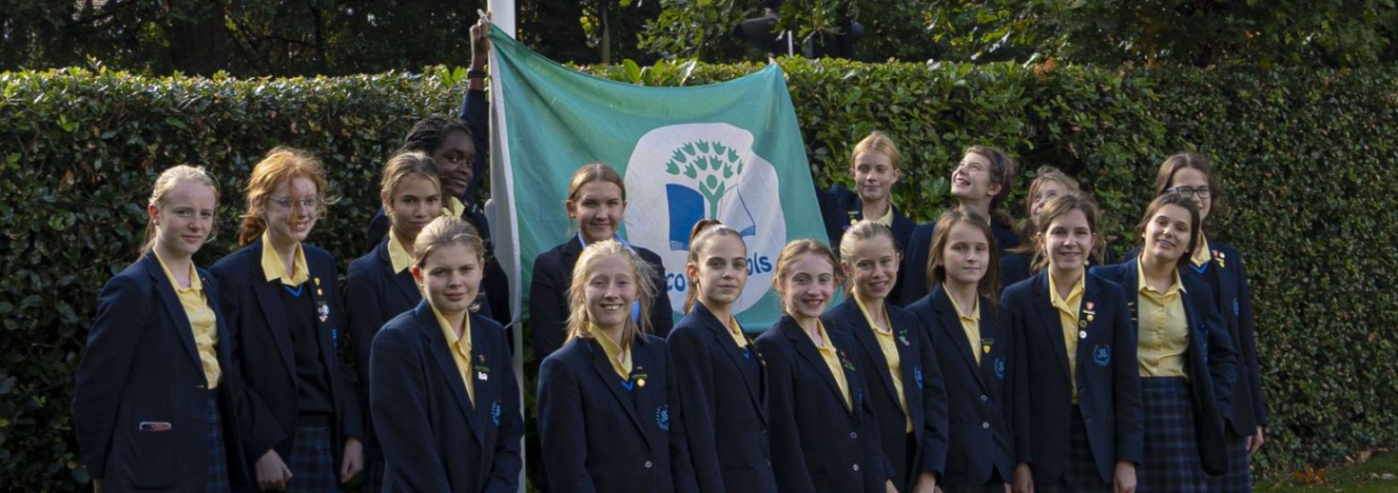 St Mary’s Senior School Eco Team standing in their uniform in front of the Eco Schools Green Flag With Distinction