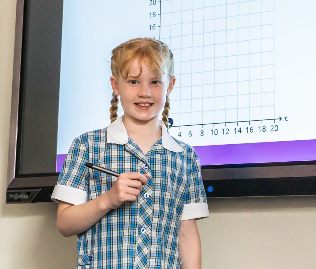 Lower school pupil at St Mary's during a maths class, standing in front of an interactive white board showing an axis