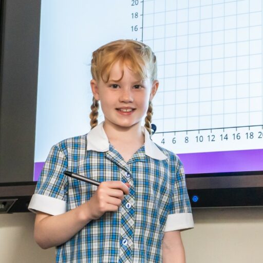 Lower school pupil at St Mary's during a maths class, standing in front of an interactive white board showing an axis