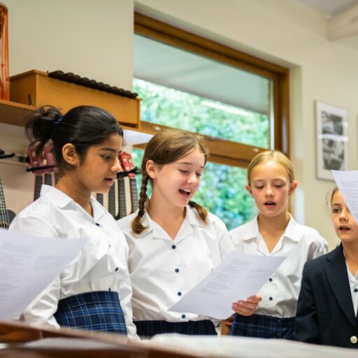 group of students in a music lesson, holding sheet paper and singing