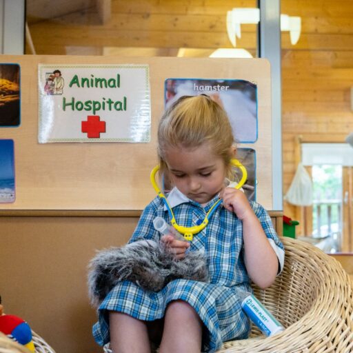 Preschool girl playing vet with a toy in the animal hospital role play area at St Mary's Kindergarten