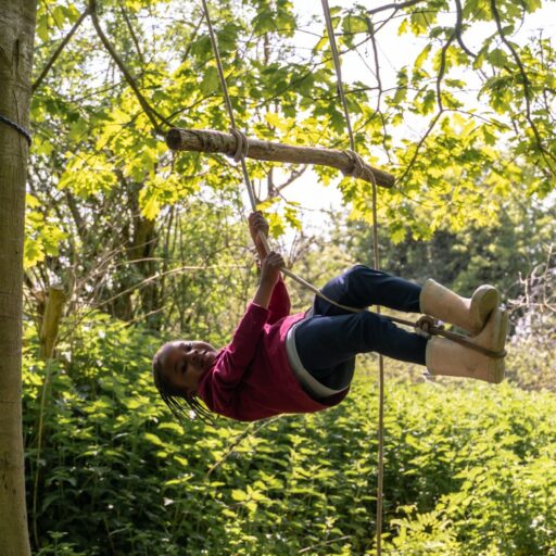 St Mary's Lower school Colchester girl swinging from a tree during a forst school lesson at St Mary's in Essex